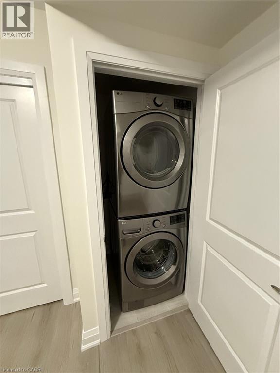 Laundry room with light wood-style floors and stacked washer and clothes dryer - 347 Canada Plum Street Unit# Lower, Waterloo, ON - Indoor Photo Showing Laundry Room