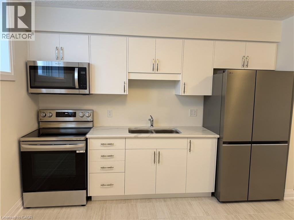 Kitchen with appliances with stainless steel finishes, white cabinets, and a textured ceiling - 347 Canada Plum Street Unit# Lower, Waterloo, ON - Indoor Photo Showing Kitchen With Double Sink