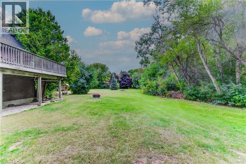 View of grassy yard with a wooden deck and view of wooded area - 685 Briardean Road Unit# Lower, Cambridge, ON - Outdoor