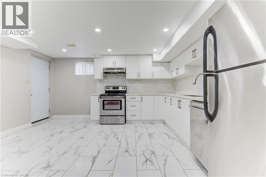 Kitchen with appliances with stainless steel finishes, white cabinets, tasteful backsplash, light marble finish flooring, and under cabinet range hood - 685 Briardean Road Unit# Lower, Cambridge, ON - Indoor Photo Showing Kitchen