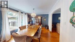 Dining area with a chandelier, crown molding, light wood-style floors, and arched walkways -