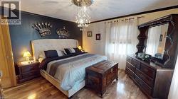 Bedroom with crown molding, wood finished floors, and a chandelier -