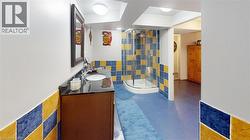 Bathroom with a shower stall, tile walls, vanity, and decorative backsplash -