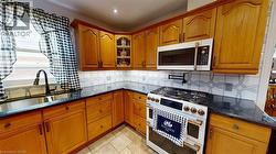 Kitchen with double oven range, dark stone countertops, brown cabinetry, stainless steel microwave, and glass insert cabinets -