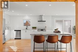 Kitchen featuring white cabinets, decorative backsplash, light wood finished floors, a breakfast bar, and recessed lighting -