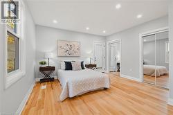 Bedroom with light wood-type flooring, recessed lighting, and two closets -