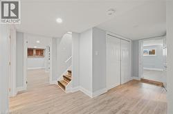 Hallway with light wood finished floors, stairway, and recessed lighting -