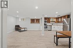 Kitchen with recessed lighting, light countertops, light wood-type flooring, appliances with stainless steel finishes, and white cabinetry -