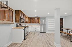 Kitchen with stainless steel appliances, light wood-type flooring, light countertops, white cabinets, and recessed lighting -