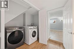 Laundry room with wood finished floors and washing machine and clothes dryer -