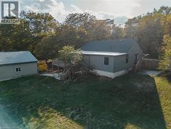 Rear view of property featuring a lawn, a wooden deck, stairway, and an outbuilding -