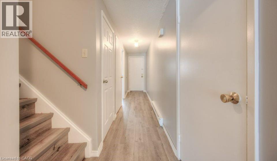 Corridor featuring stairway, light wood-style floors, and a baseboard heating unit - 1200 Courtland Avenue E Unit# 25, Kitchener, ON - Indoor Photo Showing Other Room
