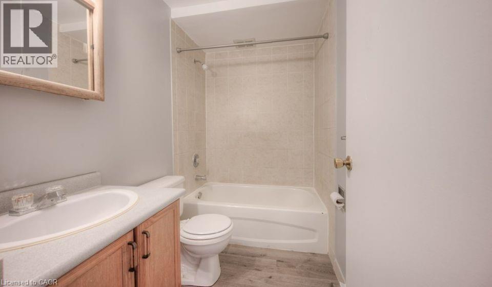 Full bathroom with vanity, washtub / shower combination, and light wood-style flooring - 1200 Courtland Avenue E Unit# 25, Kitchener, ON - Indoor Photo Showing Bathroom