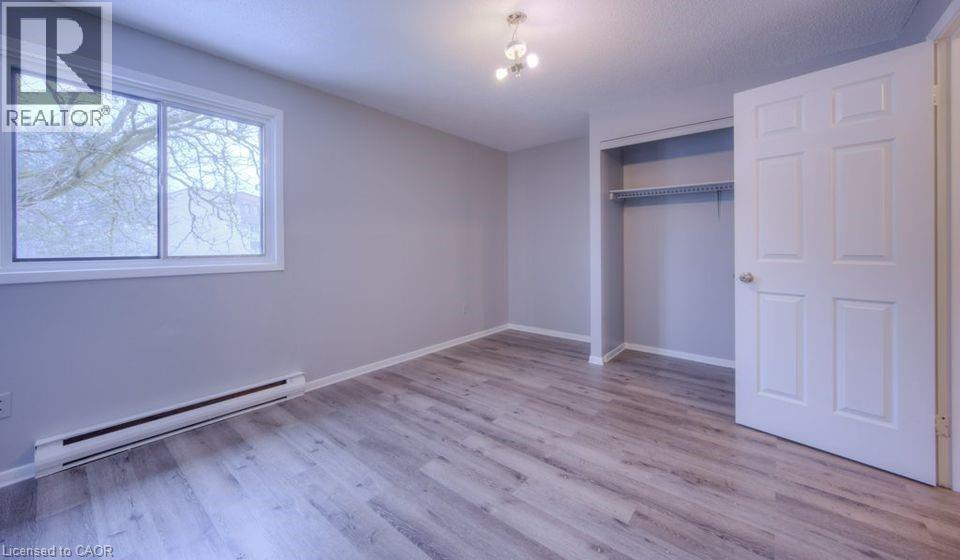 Unfurnished bedroom with baseboard heating, light wood-type flooring, and a closet - 1200 Courtland Avenue E Unit# 25, Kitchener, ON - Indoor Photo Showing Other Room