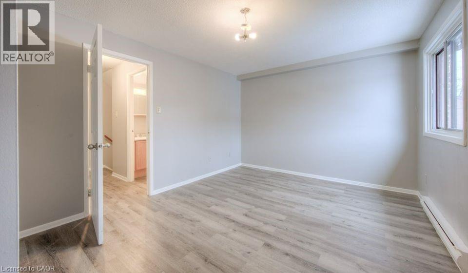 Empty room with a baseboard heating unit and light wood-style flooring - 1200 Courtland Avenue E Unit# 25, Kitchener, ON - Indoor Photo Showing Other Room