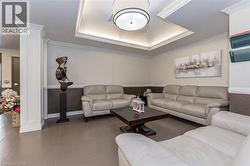 Tiled living room featuring ornamental molding, ornate columns, and a tray ceiling -