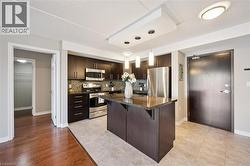 Kitchen with stainless steel appliances, a kitchen breakfast bar, dark brown cabinets, decorative backsplash, and a kitchen island -