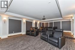 Home theater room featuring a tray ceiling, crown molding, carpet floors, and ornate columns -