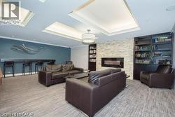 Living area featuring carpet, a stone fireplace, crown molding, a skylight, and a tray ceiling -