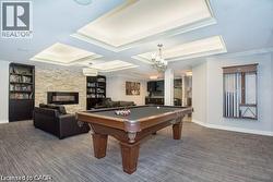 Playroom with billiards, a fireplace, coffered ceiling, and crown molding -