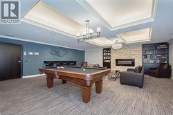 Recreation room with crown molding, built in features, carpet floors, a stone fireplace, and billiards table -