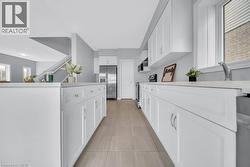 Kitchen featuring stainless steel appliances, white cabinetry, and light tile patterned floors -