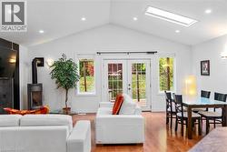 Living room featuring recessed lighting, light wood-style floors, a wood stove, lofted ceiling, and french doors -
