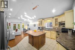 Kitchen featuring glass insert cabinets, freestanding refrigerator, electric range oven, lofted ceiling, and backsplash -