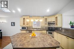 Kitchen with a kitchen island, appliances with stainless steel finishes, hanging light fixtures, a skylight, and dark stone countertops -