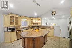 Kitchen featuring lofted ceiling, pendant lighting, a peninsula, appliances with stainless steel finishes, and glass insert cabinets -