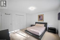 Bedroom with light colored carpet and multiple closets -