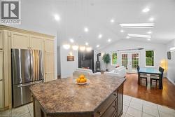 Kitchen featuring a kitchen island, french doors, freestanding refrigerator, light tile patterned floors, and vaulted ceiling -