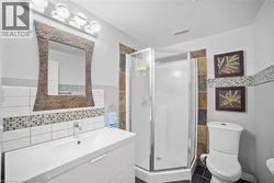 Full bath featuring vanity, tile walls, a shower stall, and dark tile patterned flooring -