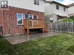 Rear view of house with brick siding, a patio area, a wooden deck, and stairway -