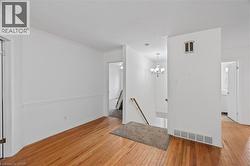 Unfurnished room featuring light wood-type flooring, a chandelier, baseboards, and crown molding -