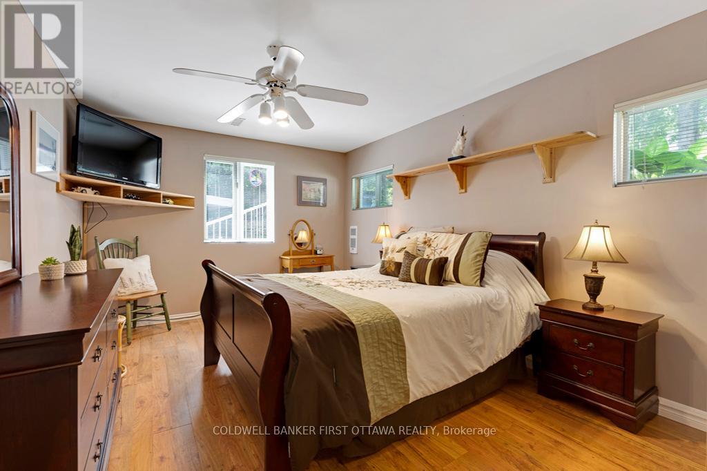 Main level bedroom has laminate plank flooring - 320 Pike Lake Route 12 Road, Tay Valley, ON - Indoor Photo Showing Bedroom