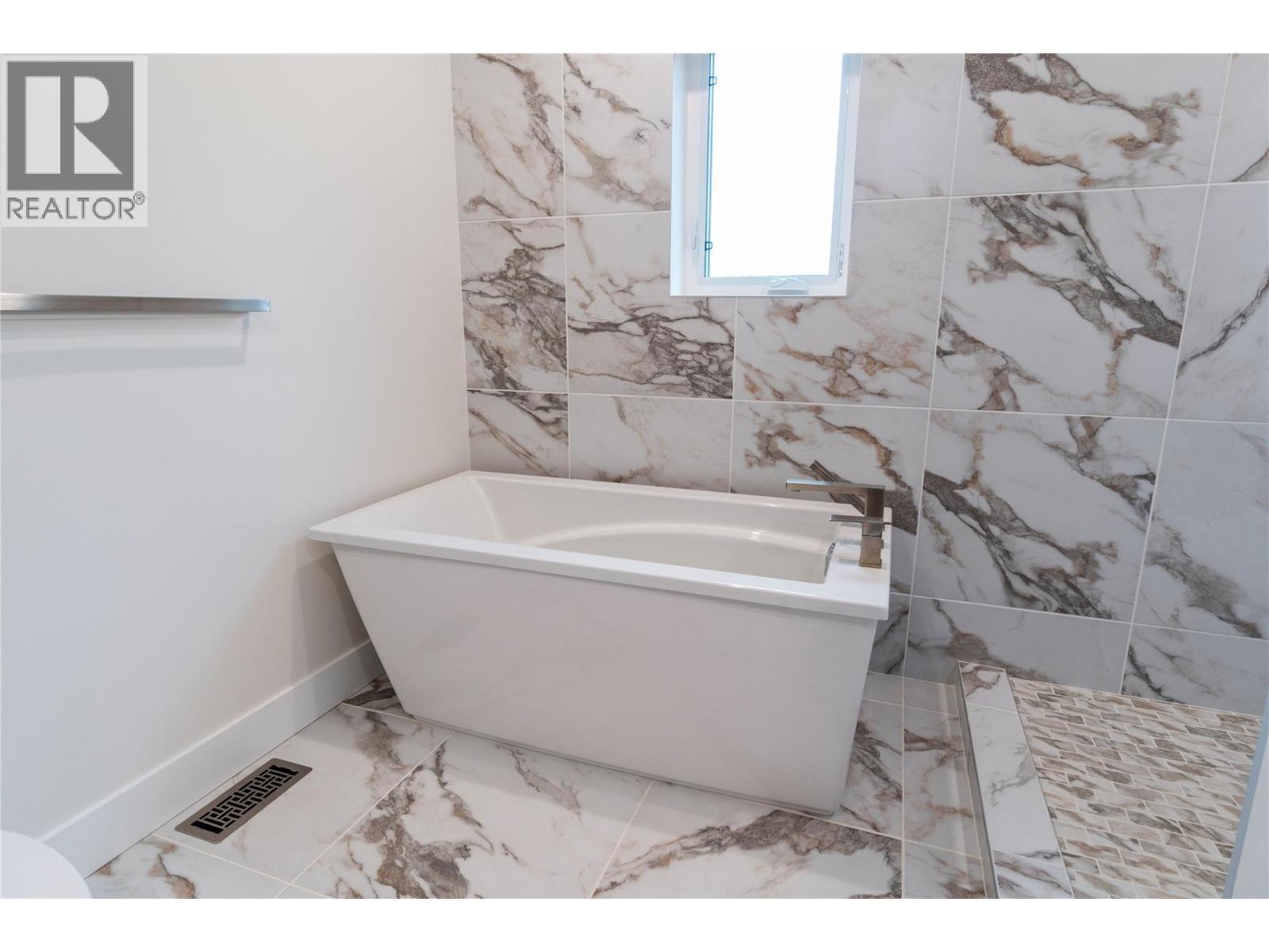 Soaker tub surrounded by beautiful tile - 633 9 Street Se, Salmon Arm, BC - Indoor Photo Showing Bathroom