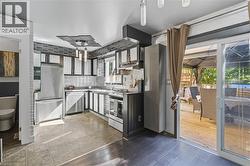 Kitchen with appliances with stainless steel finishes, backsplash, and under cabinet range hood -