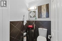 Main Floor Half bathroom with toilet and tile walls -