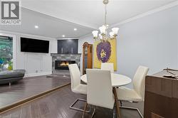 Dining space featuring a glass covered fireplace, wood finished floors, ornamental molding, recessed lighting, and a chandelier -