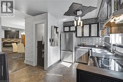 Kitchen with stainless steel appliances, ventilation hood, dark countertops, and dark cabinets -