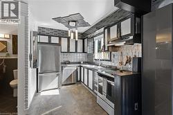 Kitchen featuring stainless steel appliances, tasteful backsplash, and under cabinet range hood -