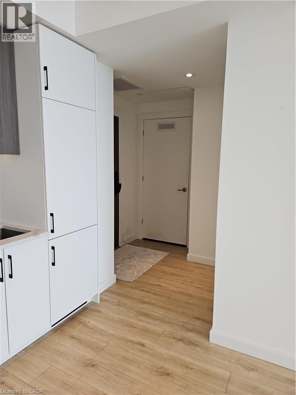 Hall with light wood-type flooring, visible vents, baseboards, and recessed lighting - 741 King Street W Unit# 1207, Kitchener, ON - Indoor