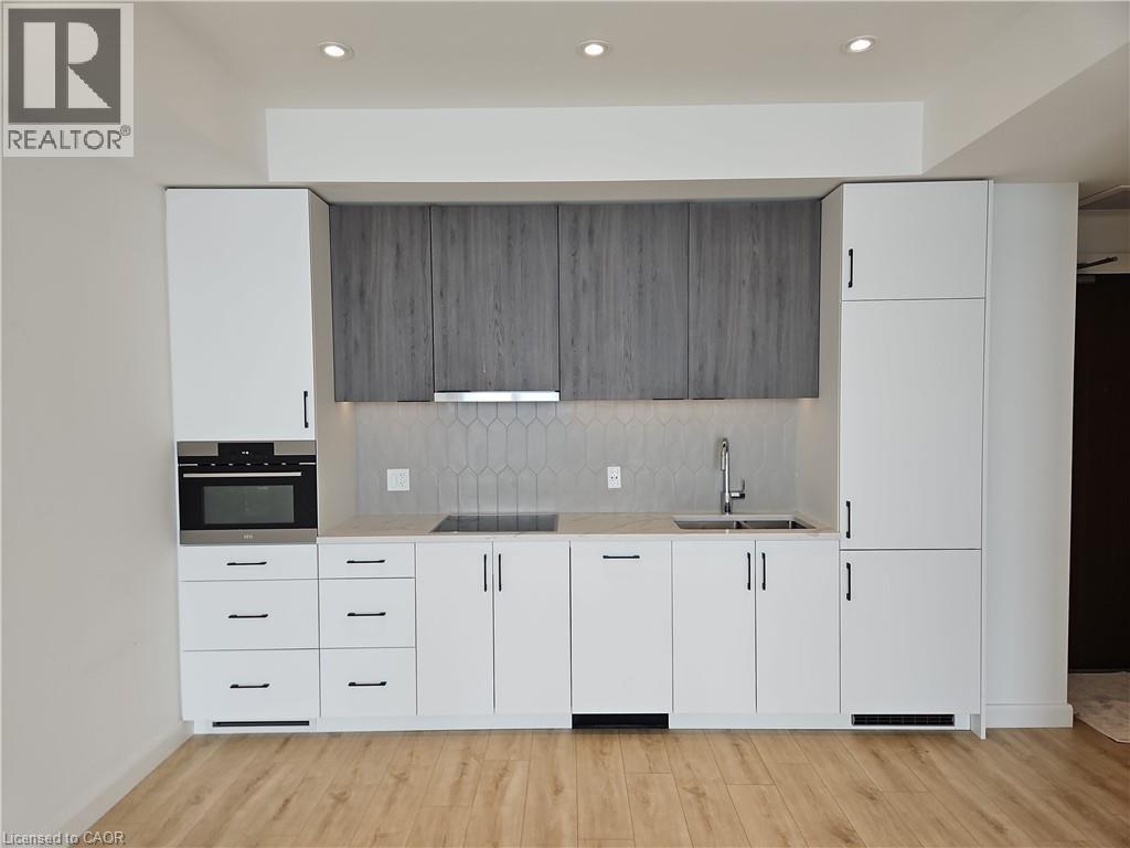 Kitchen with a sink, stainless steel oven, light countertops, range hood, and modern cabinets - 741 King Street W Unit# 1207, Kitchener, ON - Indoor Photo Showing Other Room
