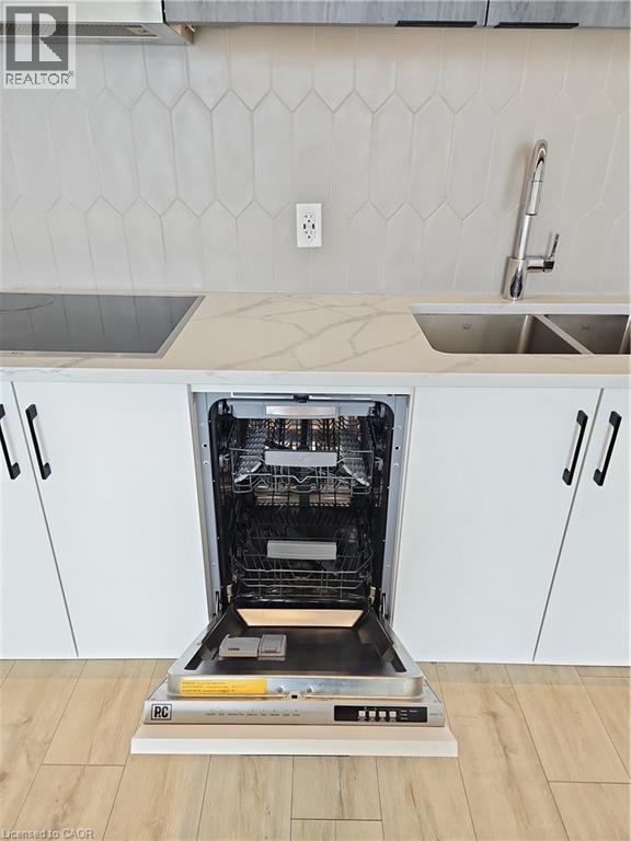 Details featuring white cabinetry, decorative backsplash, a sink, and stovetop - 741 King Street W Unit# 1207, Kitchener, ON - Indoor Photo Showing Kitchen