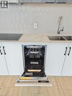 Details featuring white cabinetry, decorative backsplash, a sink, and stovetop -
