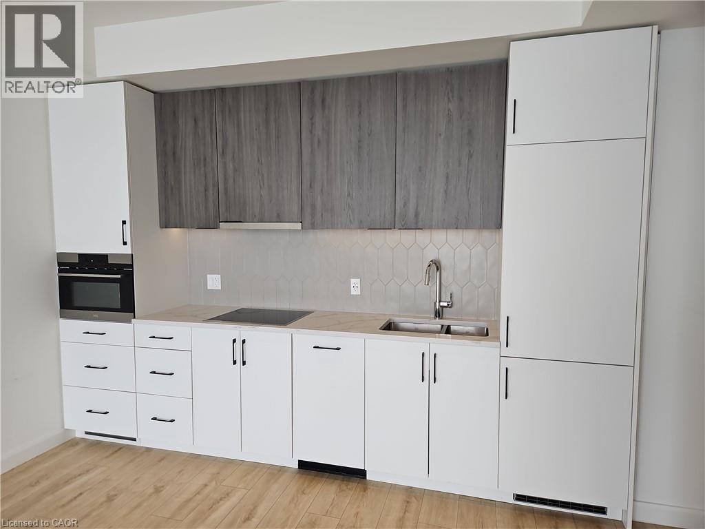 Kitchen with light countertops, a sink, stainless steel oven, and white cabinetry - 741 King Street W Unit# 1207, Kitchener, ON - Indoor Photo Showing Kitchen