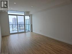 Unfurnished room with a view of city, floor to ceiling windows, recessed lighting, wood finished floors, and baseboards -