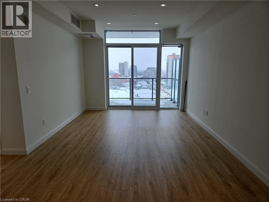 Spare room featuring visible vents, baseboards, wood finished floors, a view of city, and a wall of windows - 741 King Street W Unit# 1207, Kitchener, ON - Indoor Photo Showing Other Room