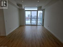 Spare room featuring visible vents, baseboards, wood finished floors, a view of city, and a wall of windows -